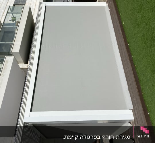 סוכך אפור גדול על מרפסת עם מסגרת מתכת לבנה